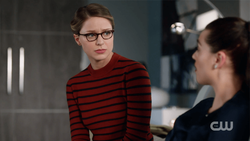 Kara sits on Lena's couch with a sympathetic look