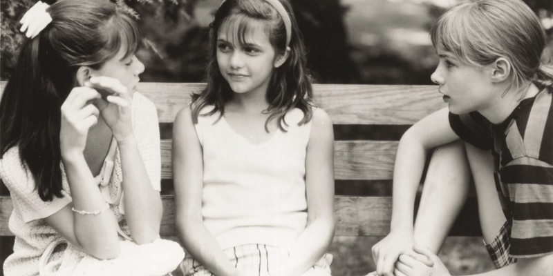 A still from the 26th best lesbian movie of all time Hide and Seek. Three young girls sit on a bench together. 