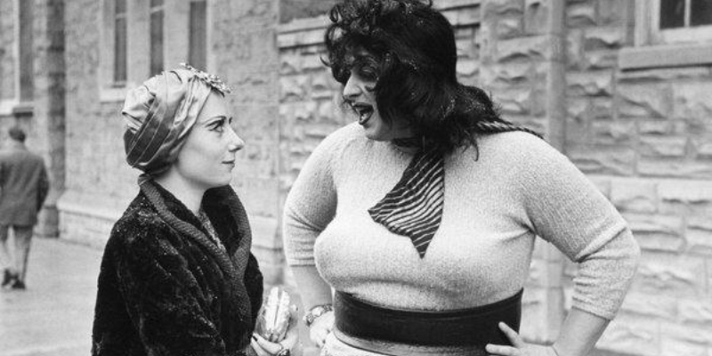 A still from Multiple Maniacs. Divine talks to Mink Stole with her arms on her waist. 