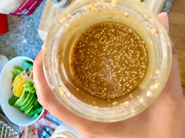 a jar with brown thick liquid inside speckled with sesame seeds