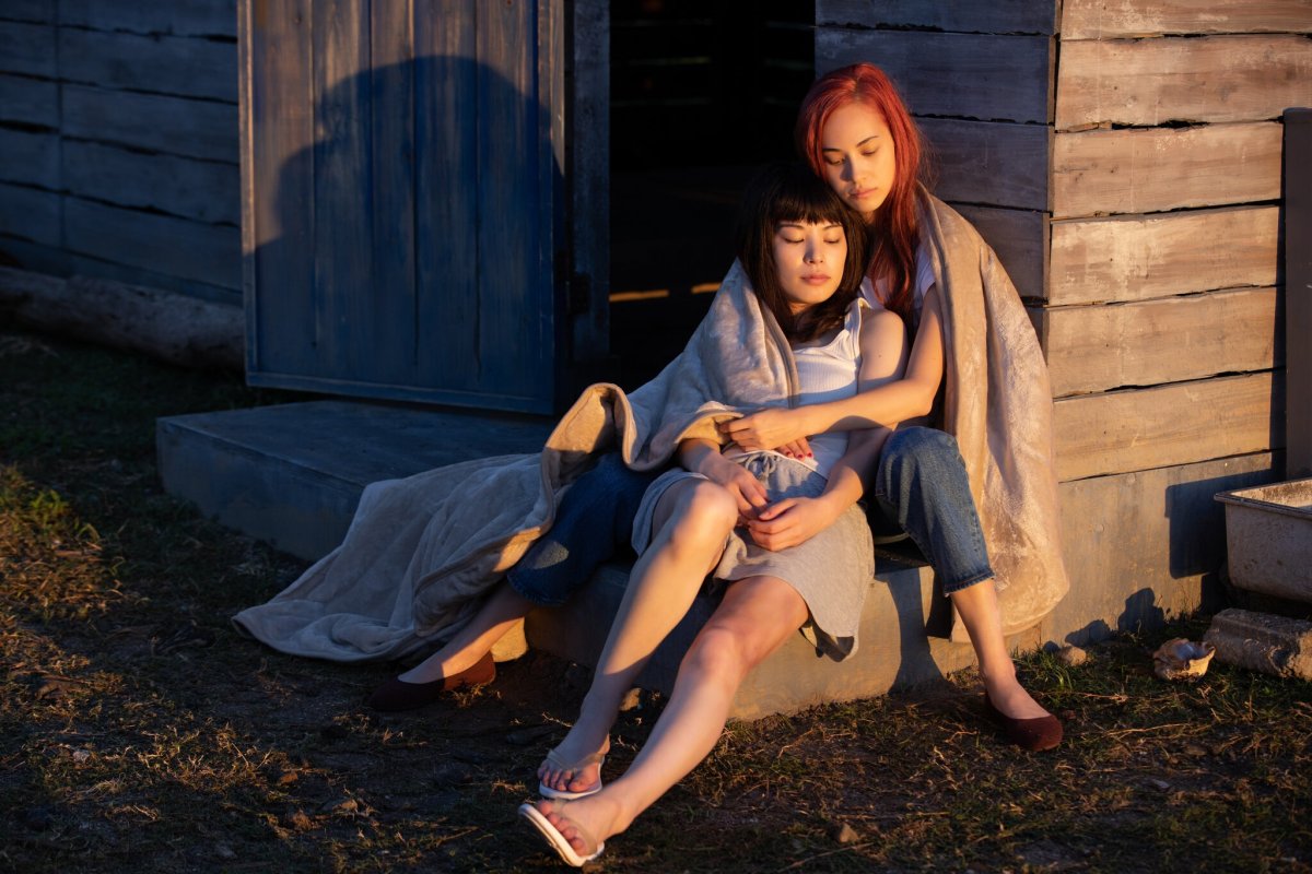 Two women holding each other sitting outside a house at sunset, still from "Ride or Die"