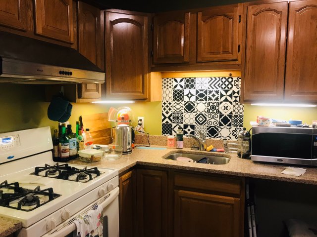 Kitchen with bright yellow walls, black and white tile mosaic, and colorful kitchen tools arranged on countertop