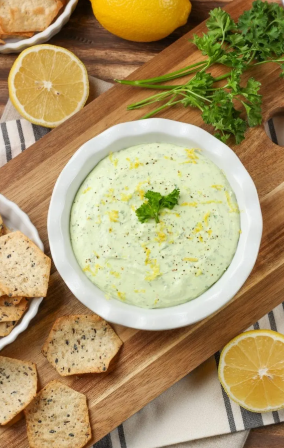 a green dip surrounded by crackers