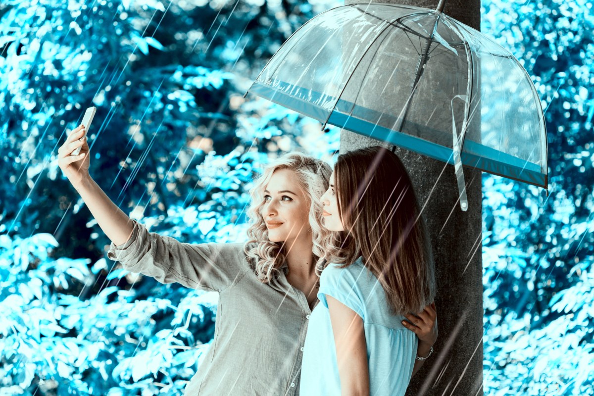 two women standing under an umbrella in the rain