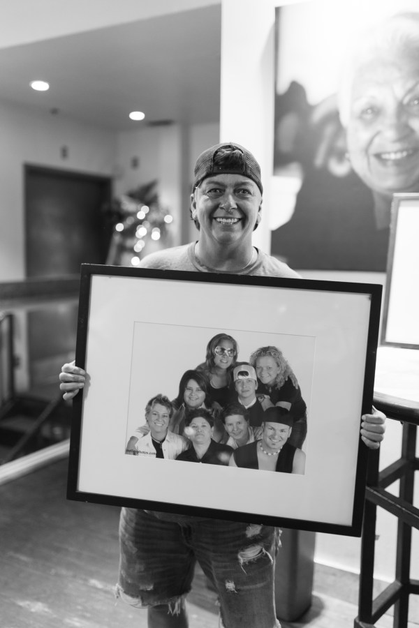 Mindy Robbin posing with a photo of her and the rest of the Sue Ellen’s staff in 2003.