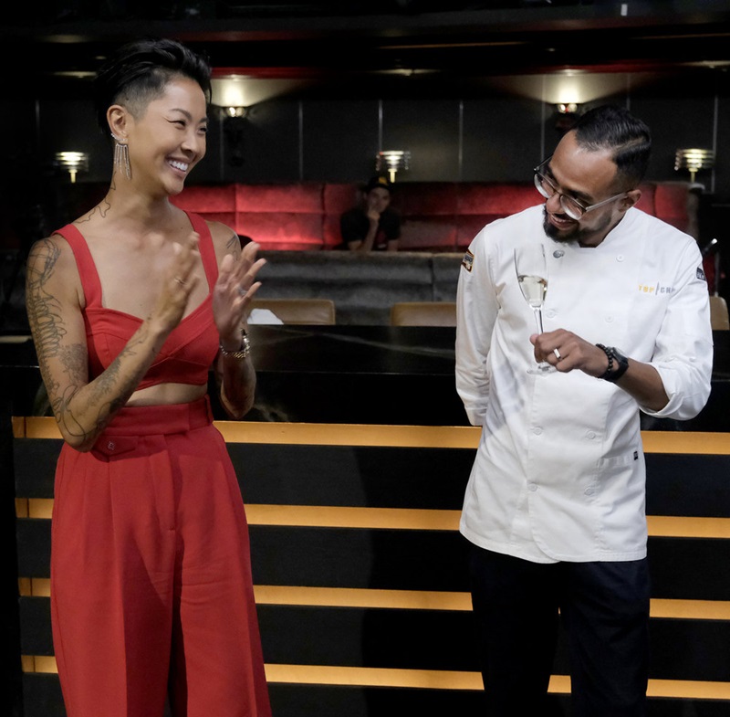Kristen Kish, in a matching red halter and pants, applauds the new Top Chef.