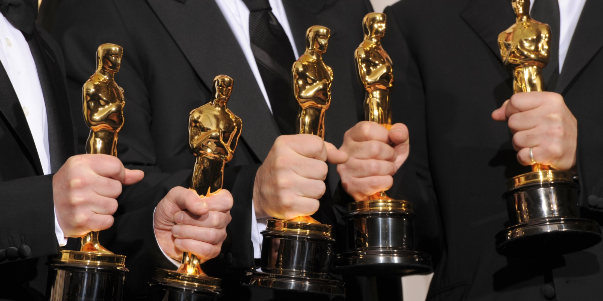 Five white hands grip Oscars