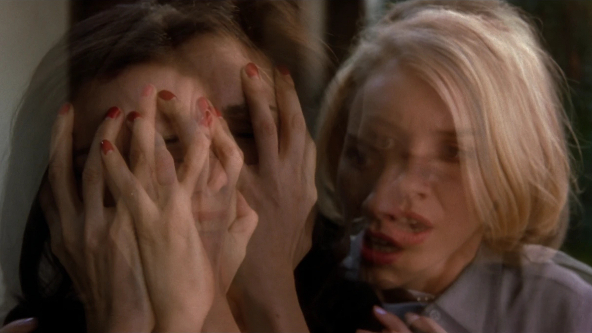 A fractured image of a brunette covering her face and a blonde looking on. 