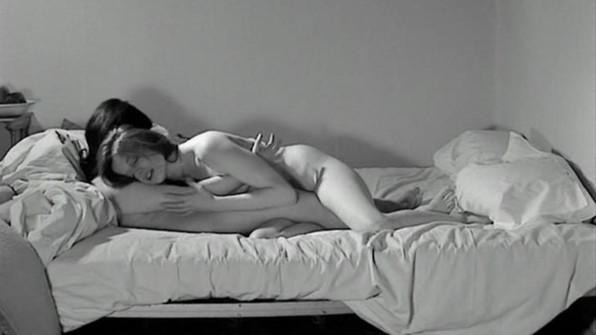 A black and white image of two women naked in bed together.