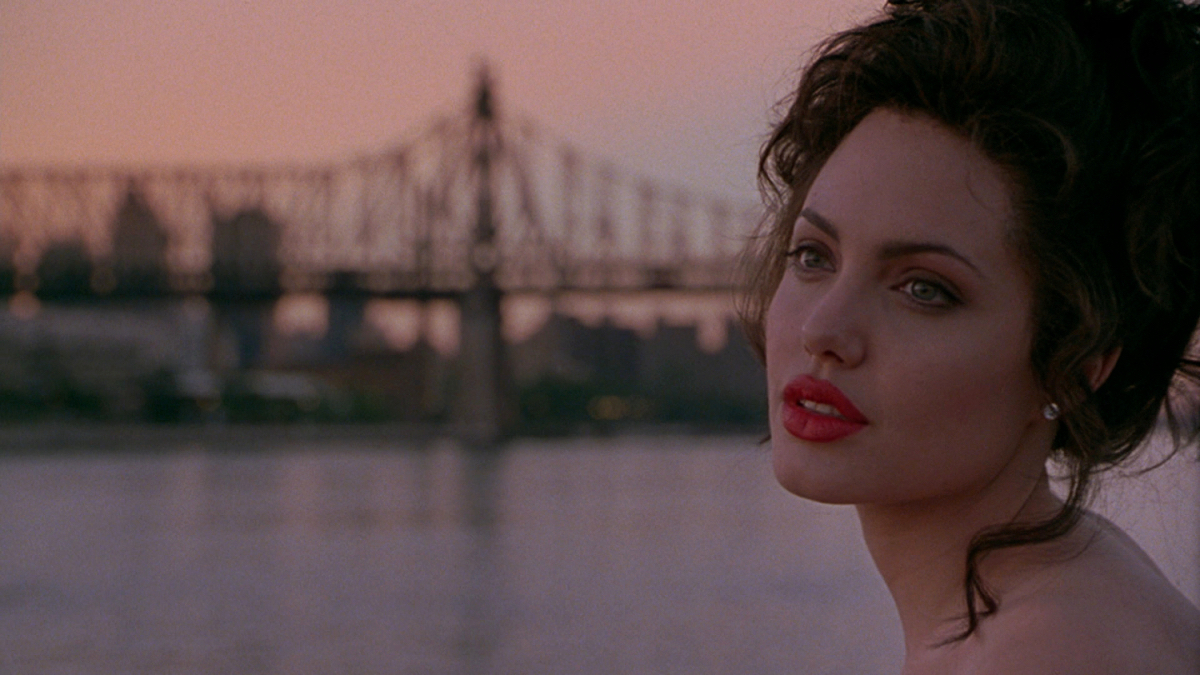 Angelina Jolie in glamour makeup with a bridge behind her.