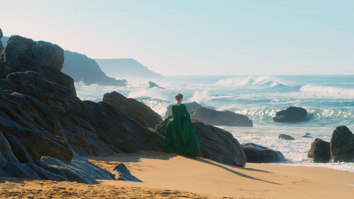 Best lesbian movies #4:a woman in a green dress looks out at crashing ocean waves.