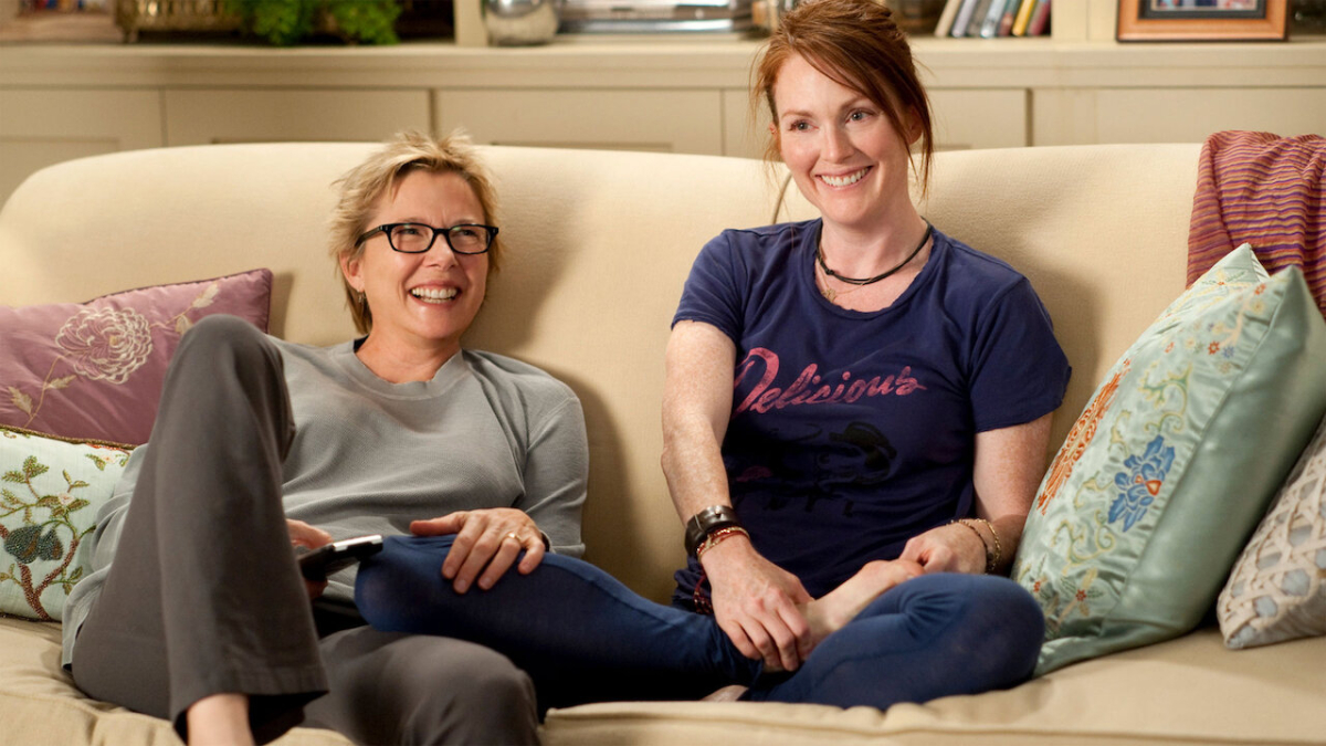Best lesbian movies #45: Annette Benning and Julianne Moore sit next to each other on a couch and laugh.