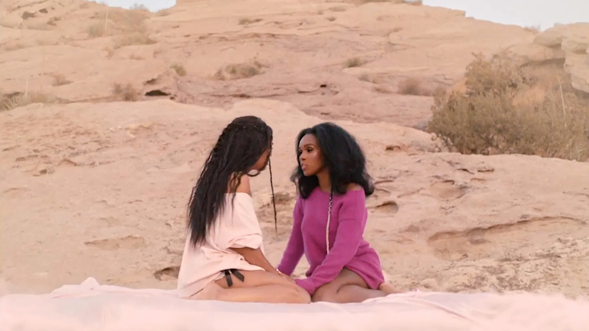 Janelle Monáe and Tessa Thompson gaze at each other dressed in pink in the desert.