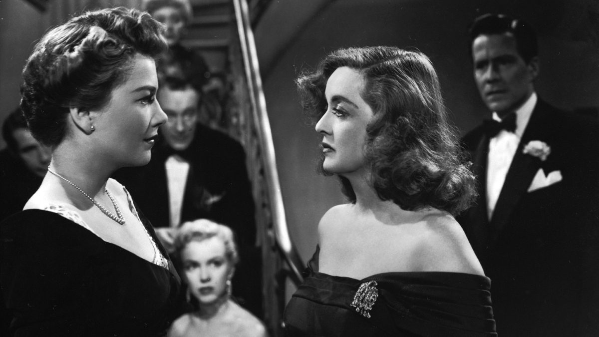 Bette Davis and Anne Baxter face off as the rest of the cast looks on.