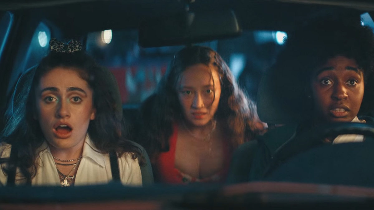Best lesbian movies #9: Ayo Edebiri and Rachel Sennott sit in the front seat of a car with Havana Rose Liu in the back. They all look surprised.