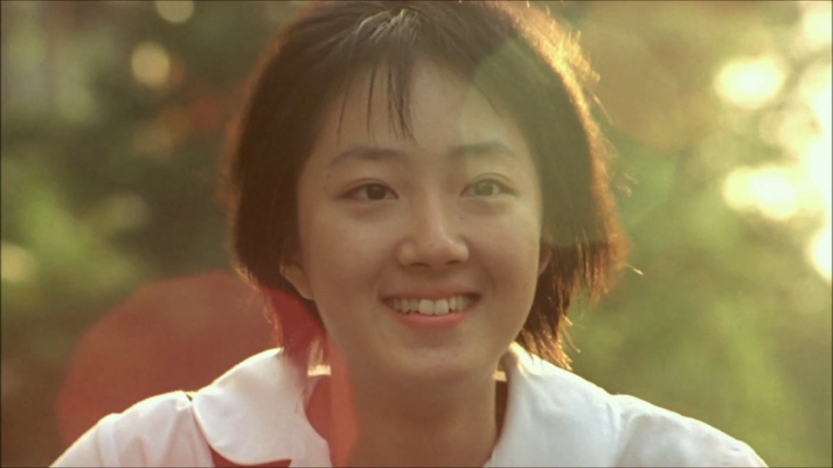 A close up of a smiling girl's face with lens flare from the sun