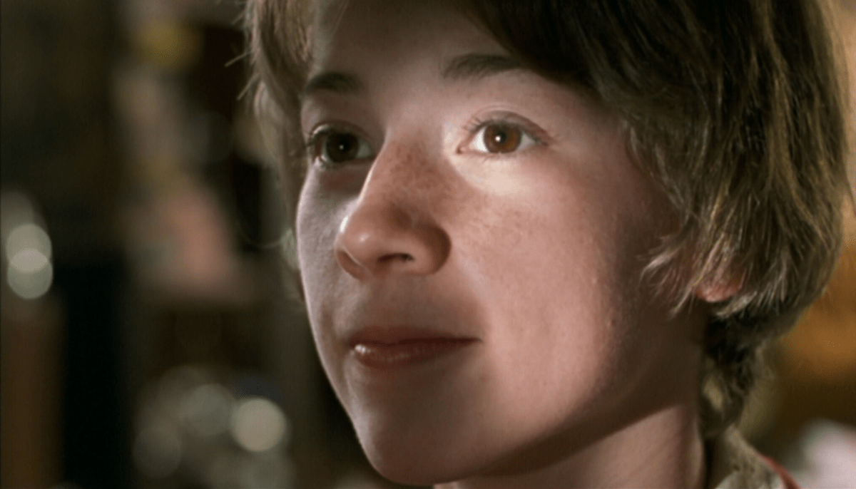 A close up of a girl's face with short hair, a crack of light illuminating half her face