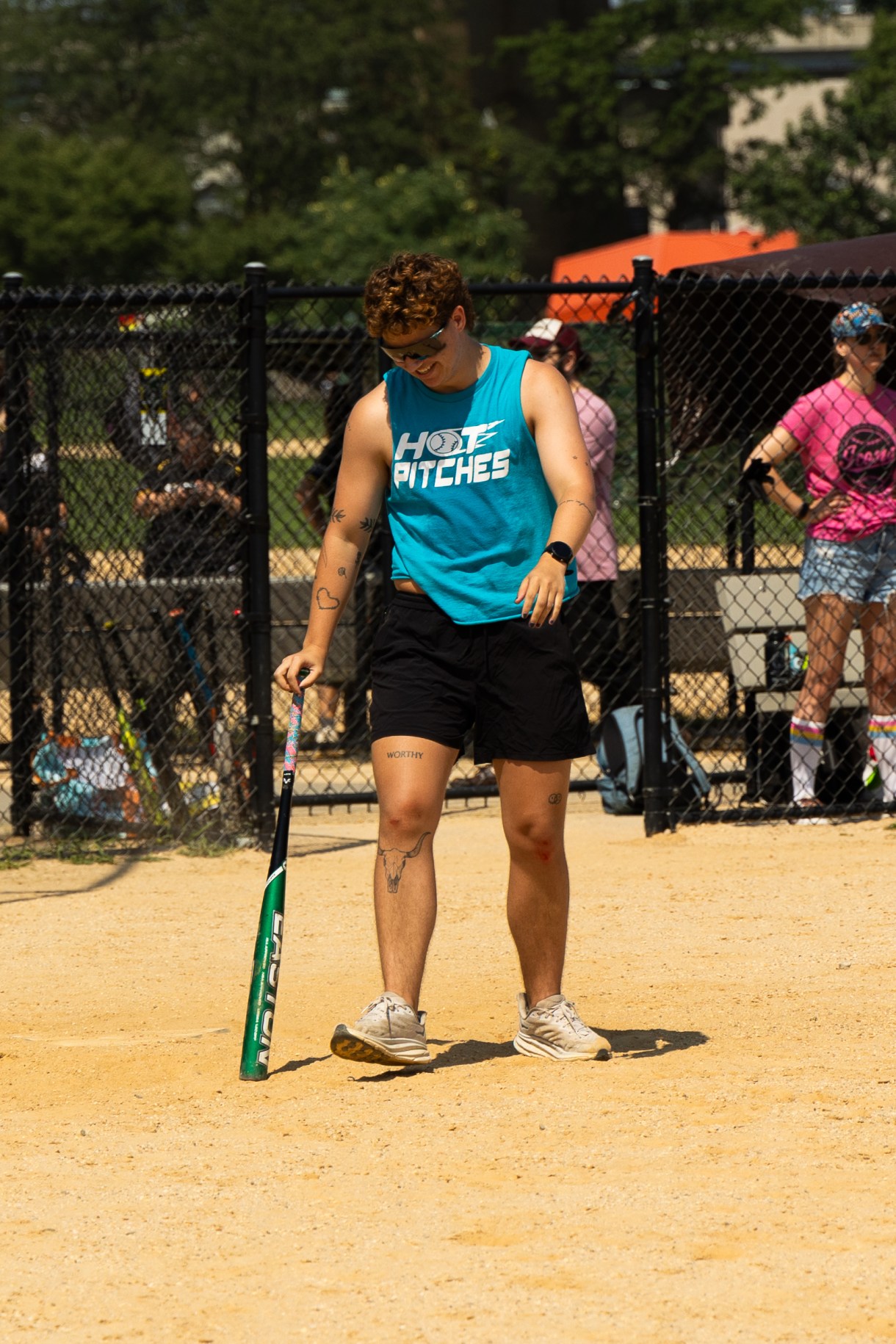 a person in a HOT PITCHES tank holds a baseball bat