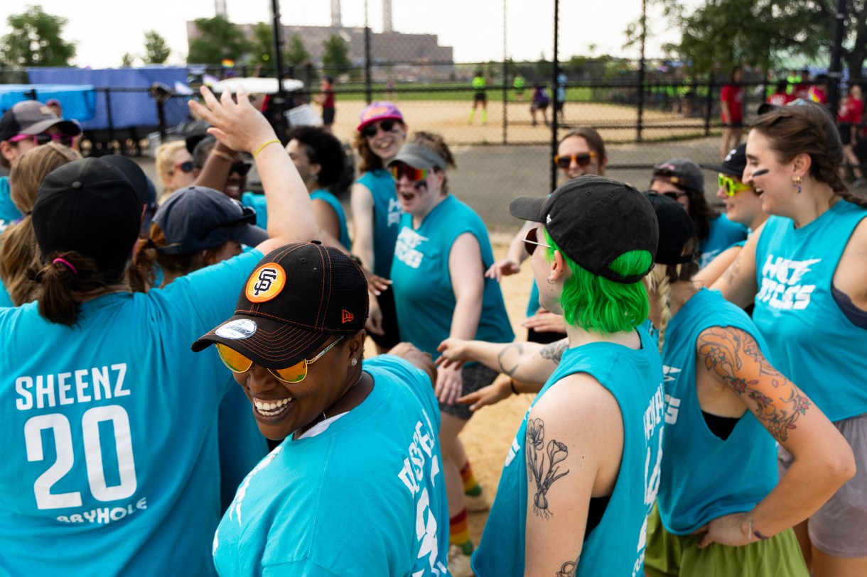 a team in blue shirts celebrates a softball game