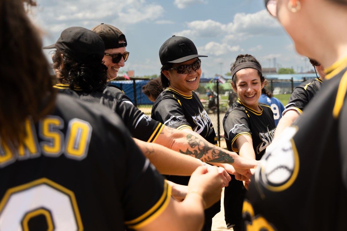 a group hands in moment on the softball field