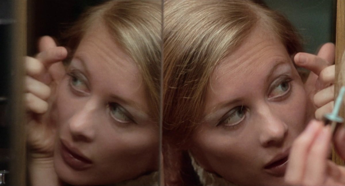 A close up mirror shot of Shirley Knight doing her make up in The Rain People