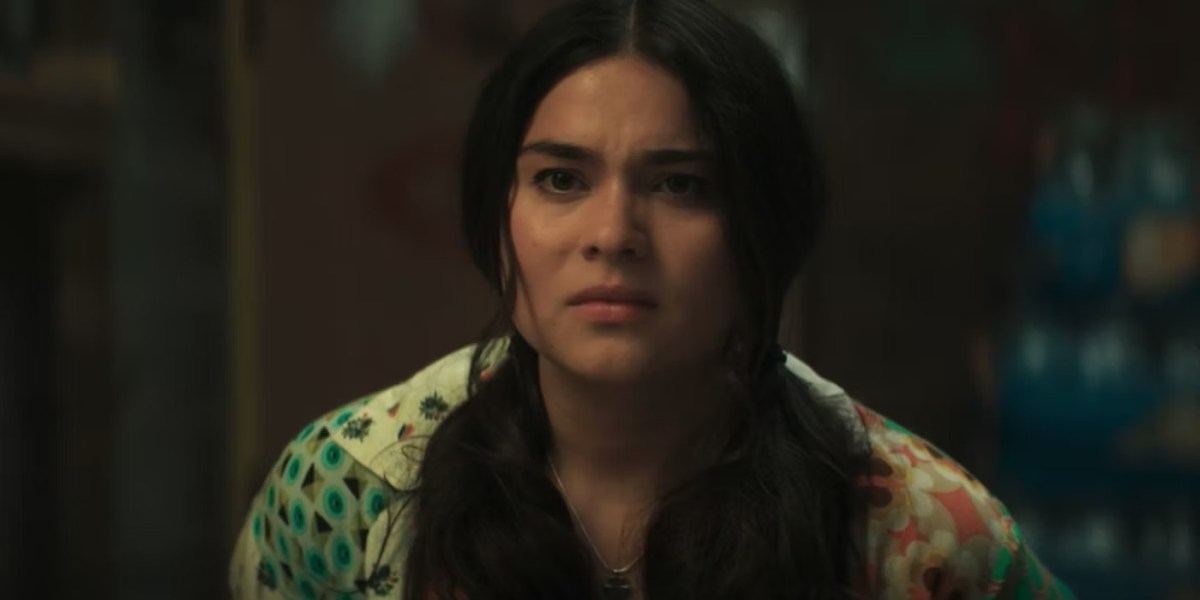 A close up of Devery Jacobs in a colorful patterned shirt looking concerned in Echo