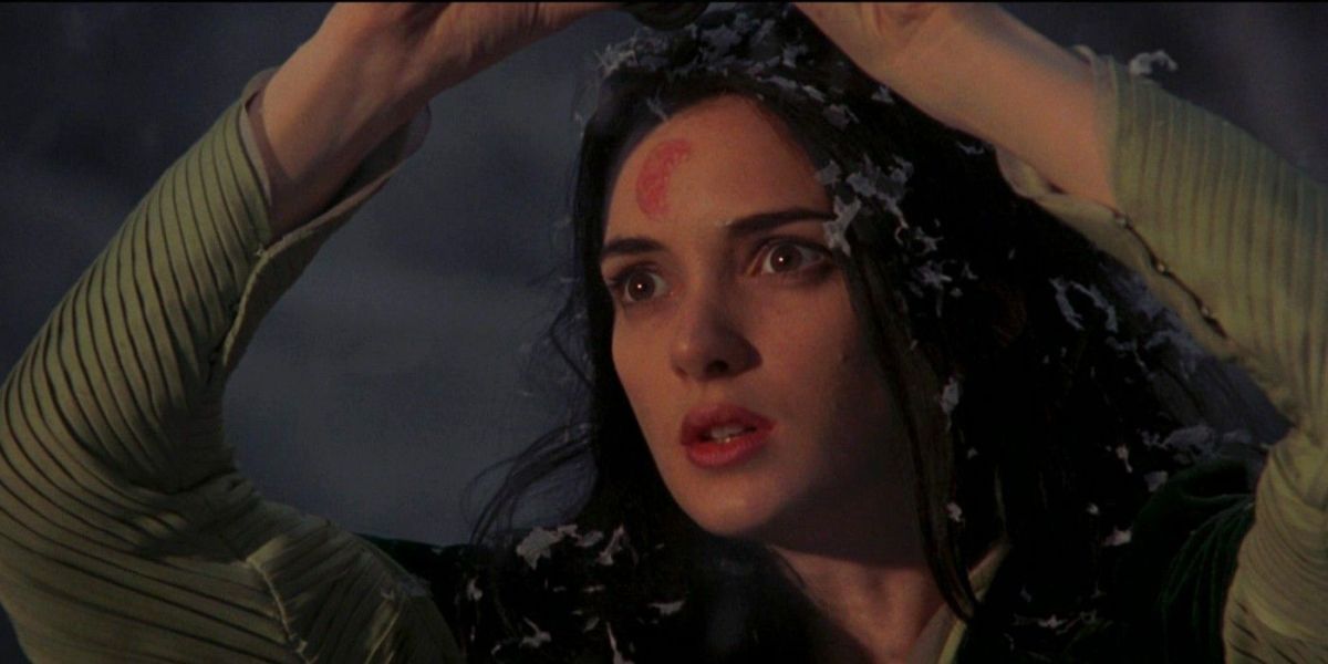 Winona Ryder lifts her arms up and looks wide eyed with blood on her face.