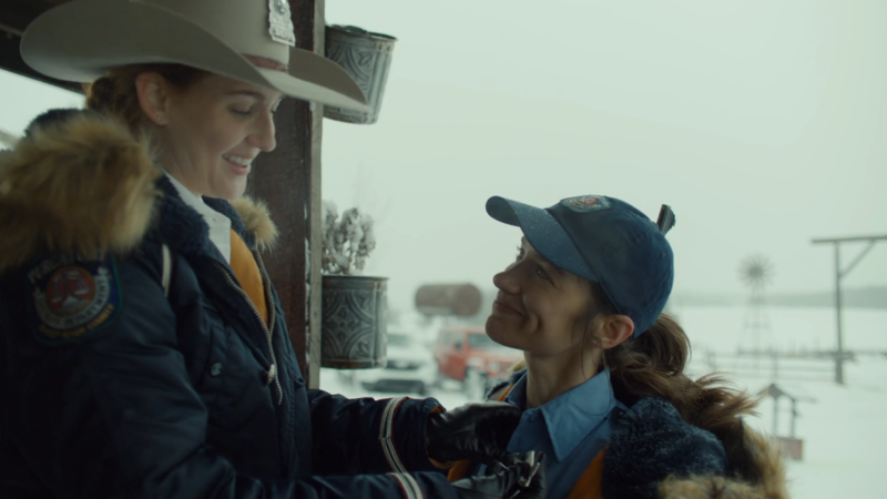 wynonna earp vengeance: wynonna in a baseball cap smiles up at nicole in a stetson