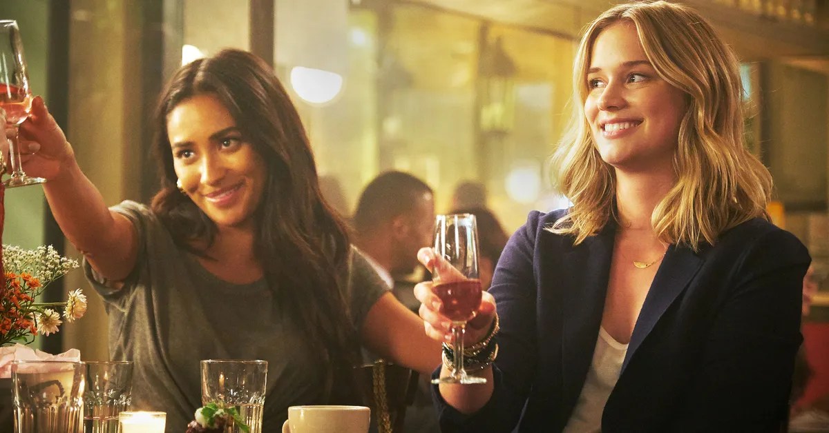 Two girls at a bar toasting and happy