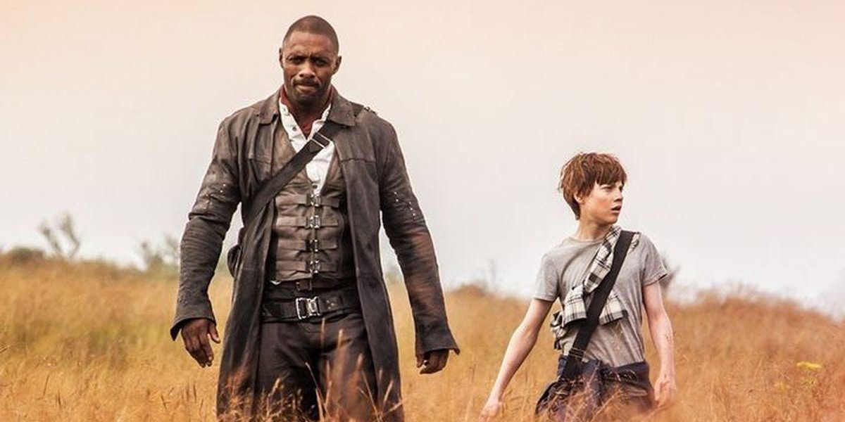 Idris Elba walks through a field of wheat alongside a kid in The Dark Tower