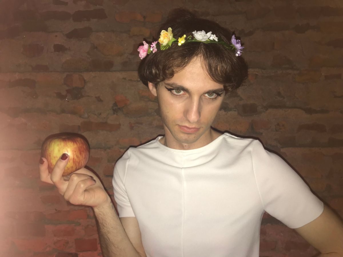 Drew, dressed as the girl with short hair from Daisies, holds an apple