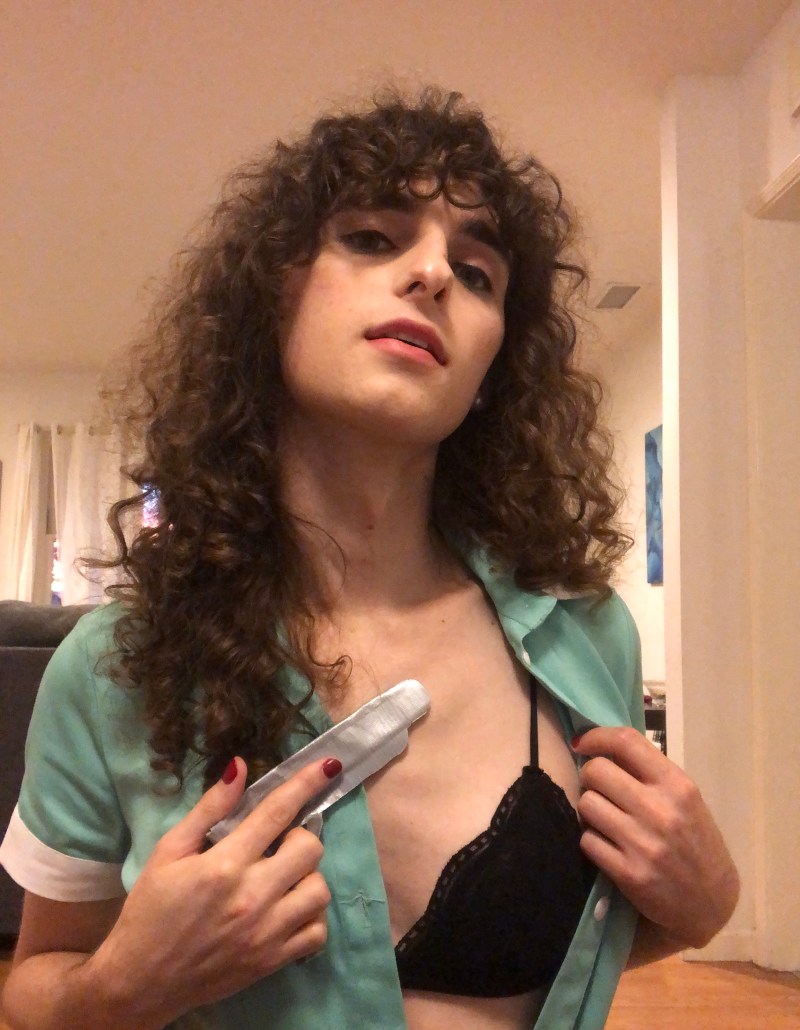 Drew poses with a fake duct tape gun on her chest flashing a black bra from under an old fashioned waitress dress