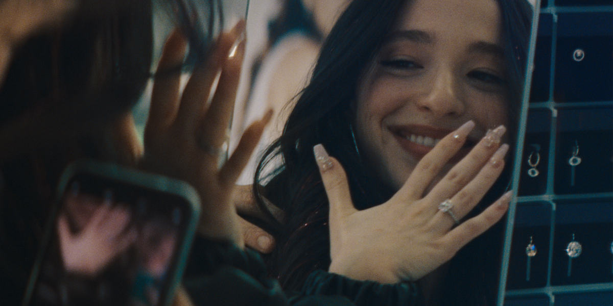 Mikey Madison as Anora holds her hand up to a mirror to admire her wedding ring.