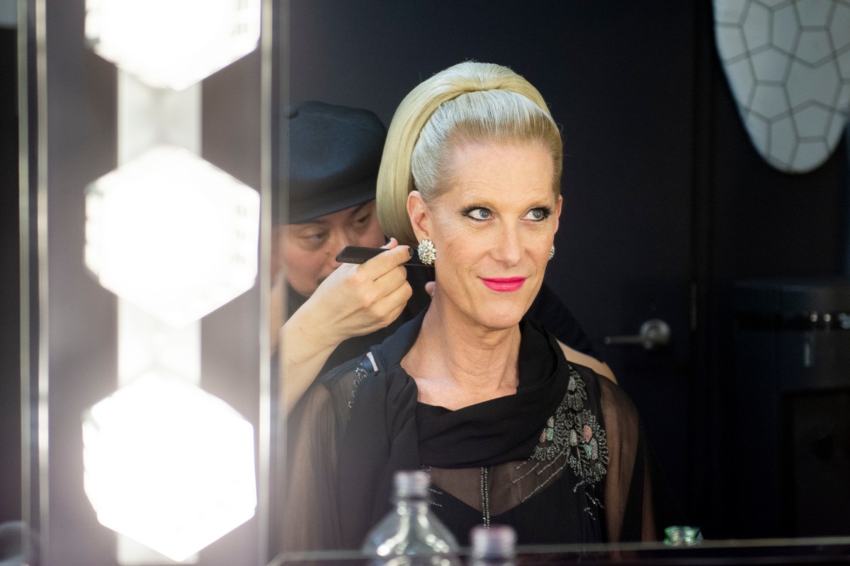 Justin Vivian Bond looks in a mirror and smiles as they get their hair done.