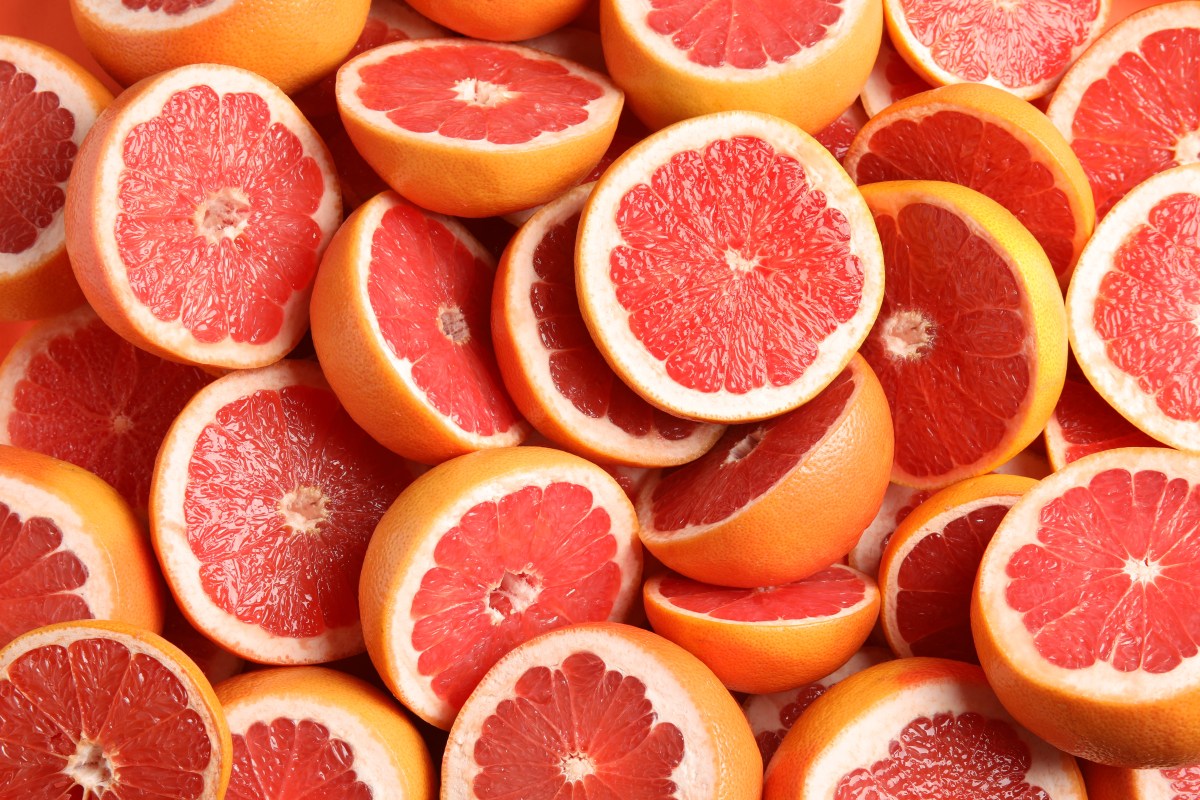 Many sliced fresh grapefruits as background, top view