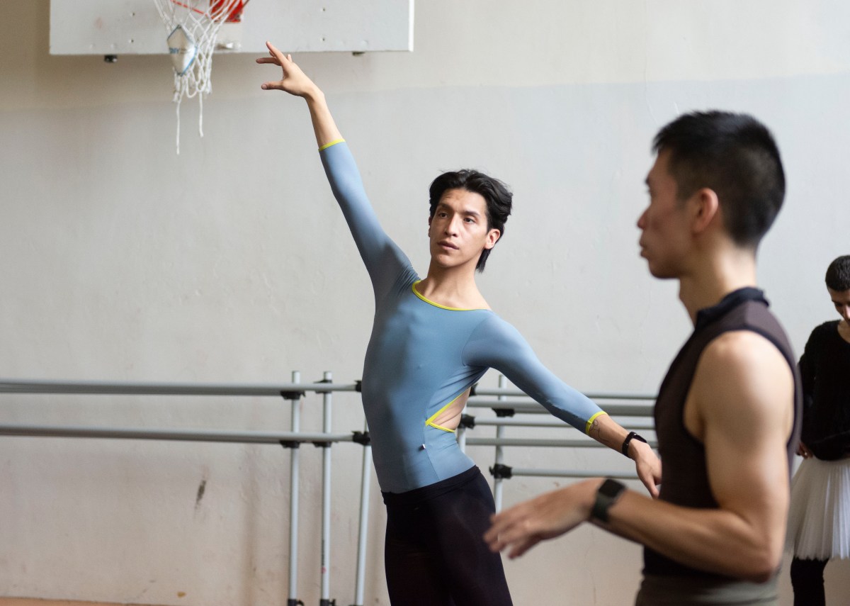 A dancer stretches out an arm in studio space.