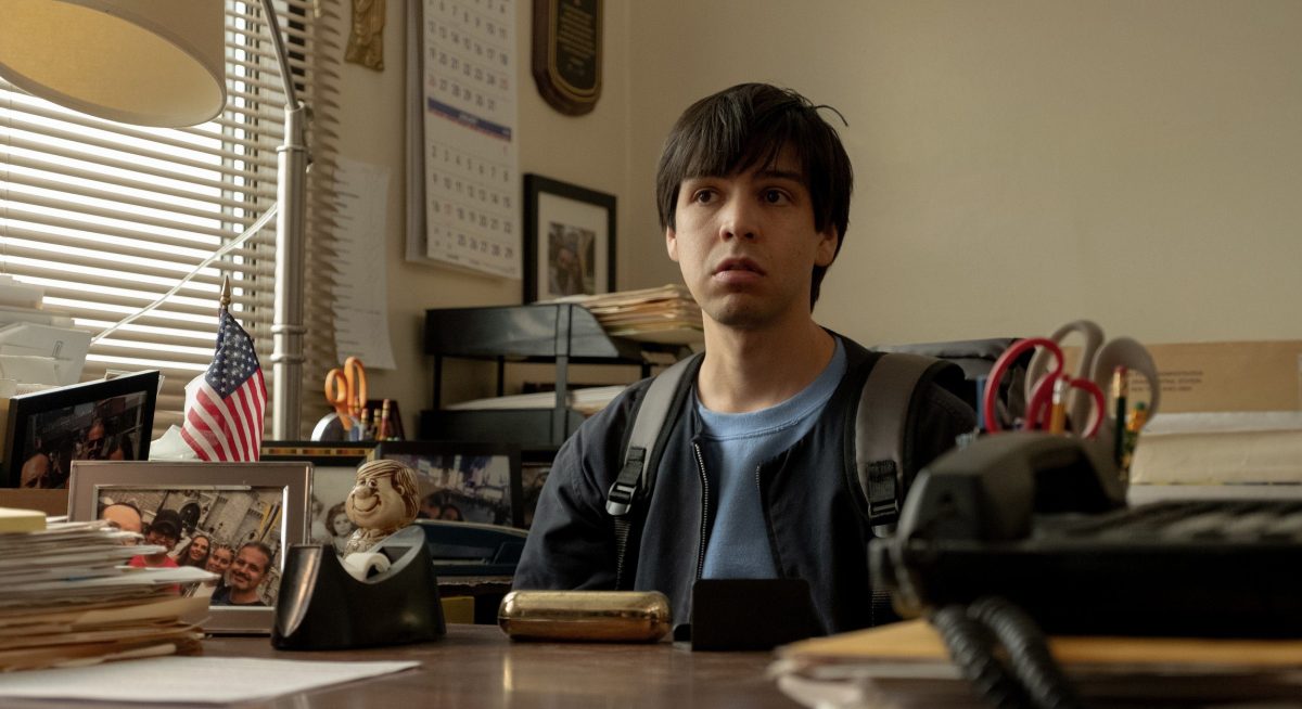 Julio Torres sits at a desk in a law office in Problemista.