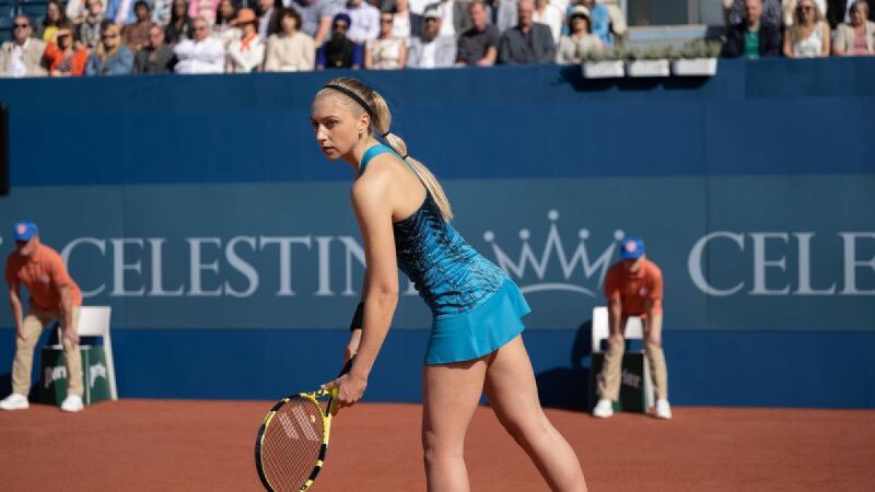 A blonde girl prepares to serve during a tennis match