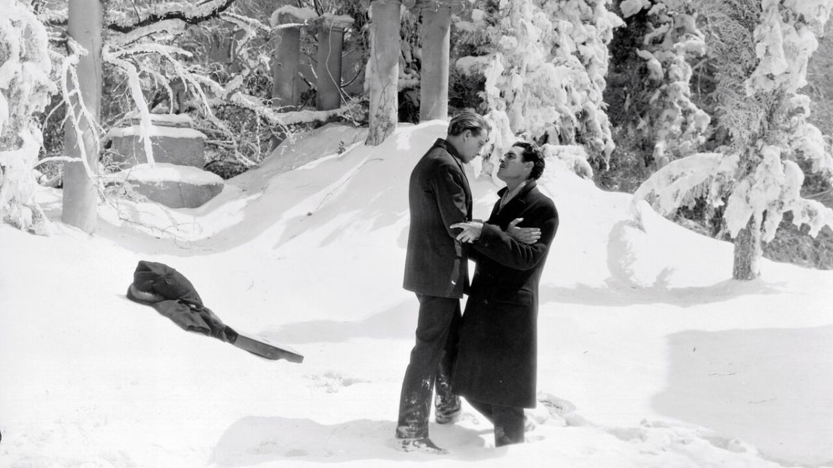 A black and white image of two men holding each other in the snow.