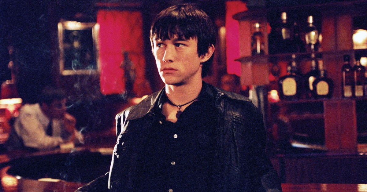 Joseph Gordon-Levitt in a leather jacket looks off at a bar.