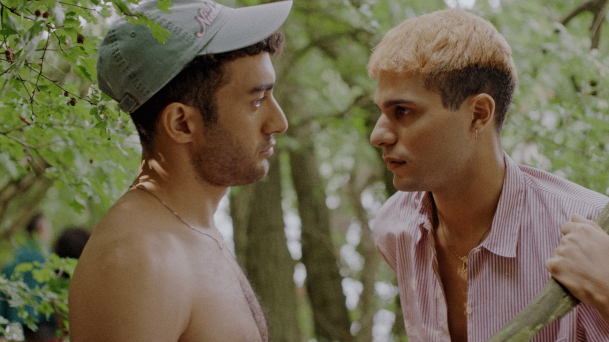 Two Iranian German men look at each other outside.