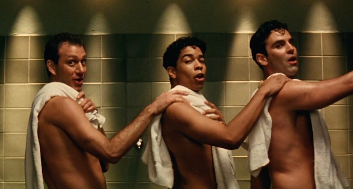 Three men sing and dance in the shower.