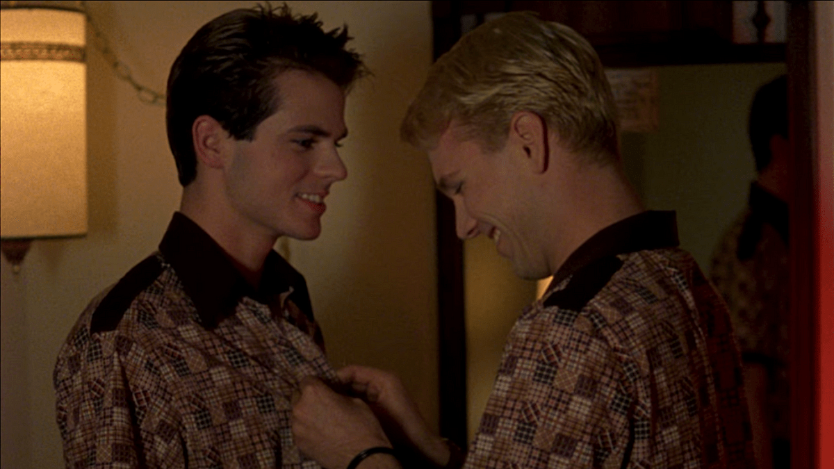 Two boys smile as they stand face to face wearing matching shirts.