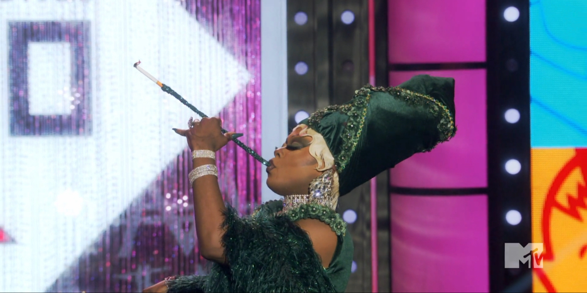 RuPaul's Drag Race episode 1703: Onya in emerald in profile smokes from a long cigarette holder