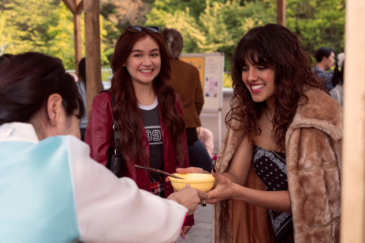 Kitty looks on as Praveena accepts of bowl of food from a vendor at a KISS event.