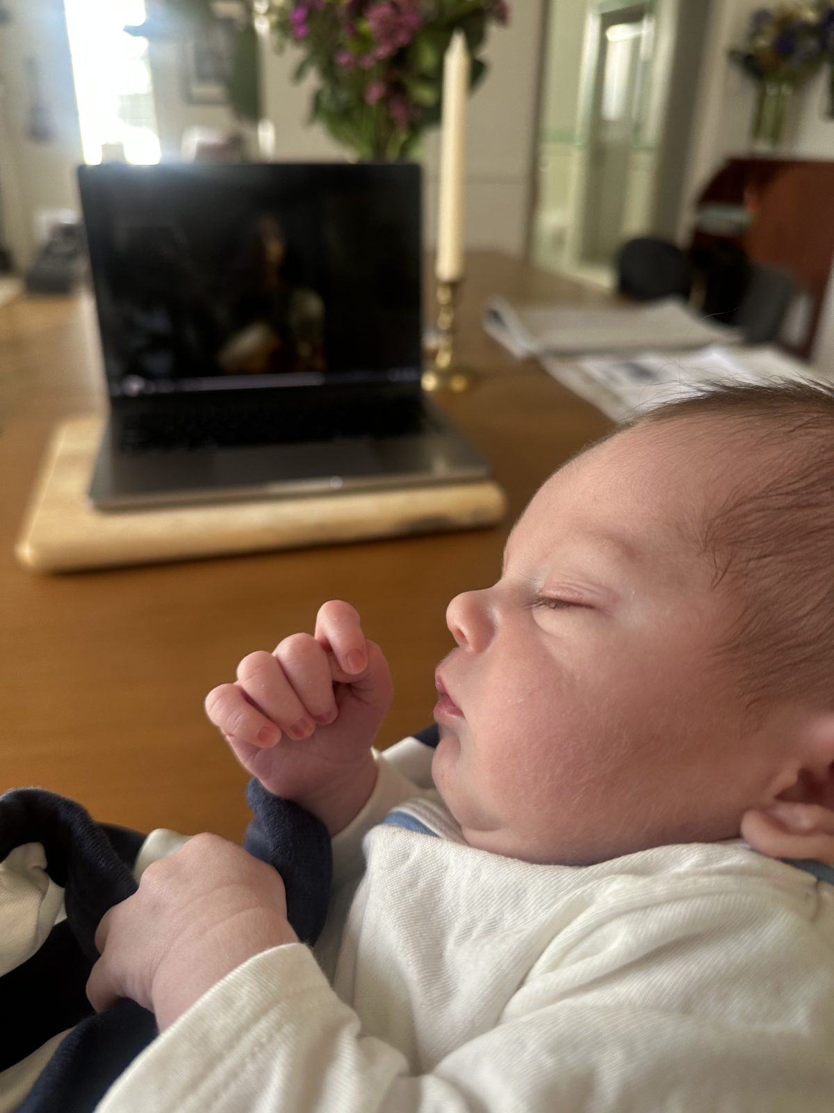 A sleeping baby with a laptop behind him