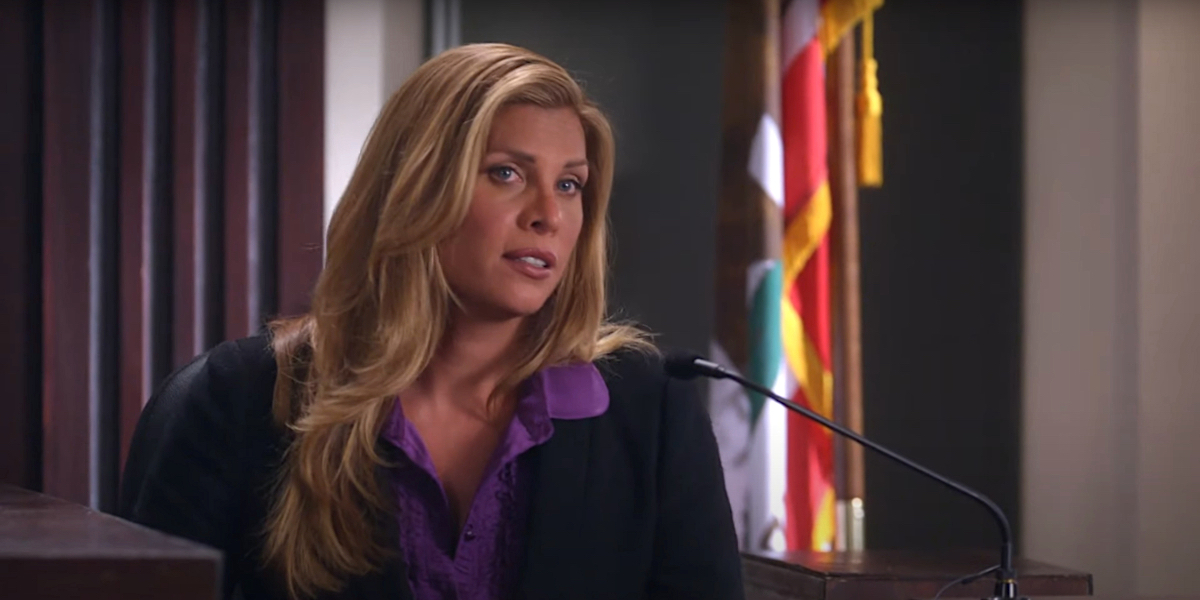 Candis Cayne in Drop Dead Diva season two episode eight, she takes the stand in a court room wearing a black jacket and a purple button down shirt