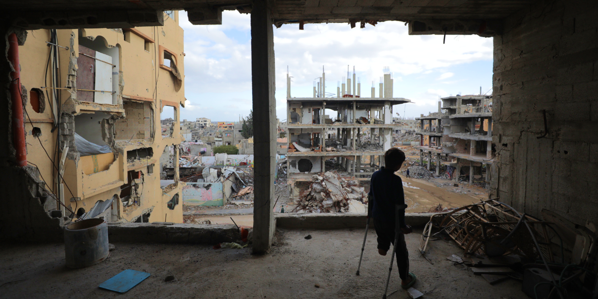 a young amputee in Gaza looking out at buildings destroyed by Israel