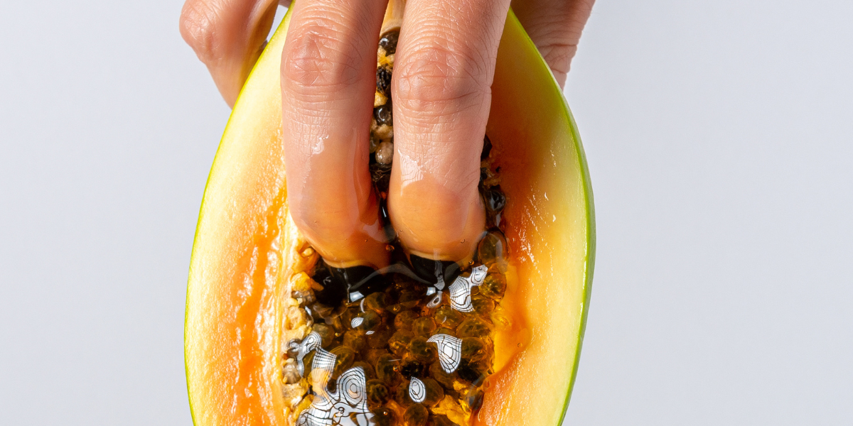 two fingers going into a papaya