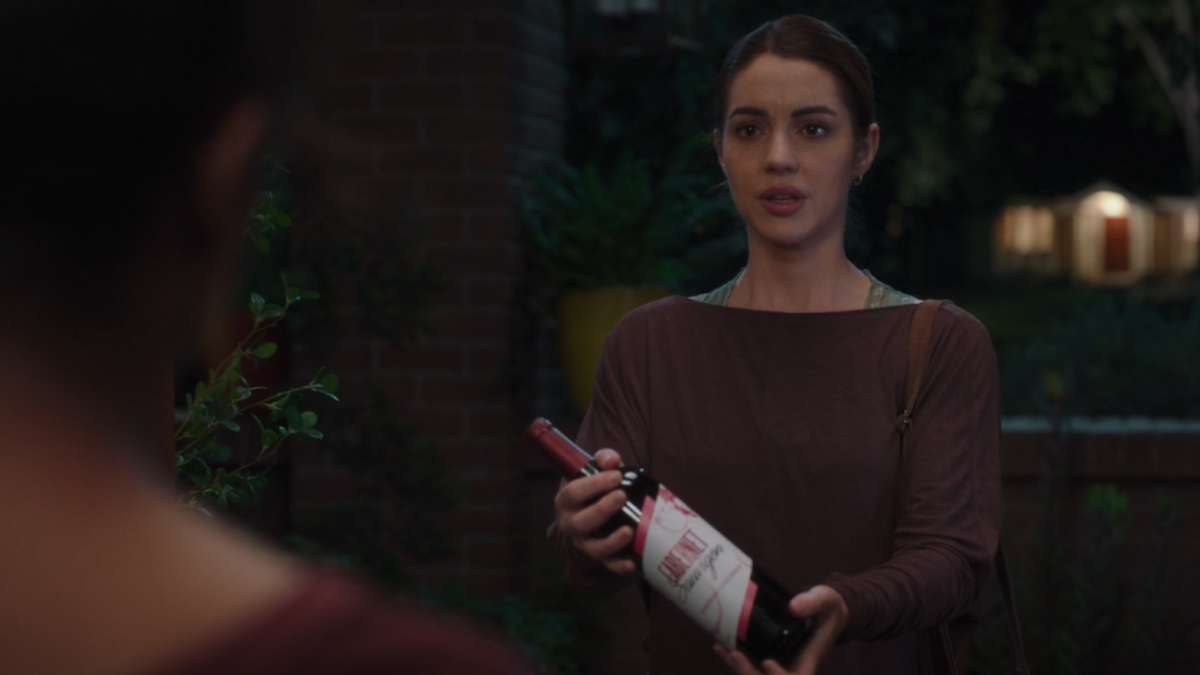 Jules holds out a bottle of wine as an offering of apology and forgiveness